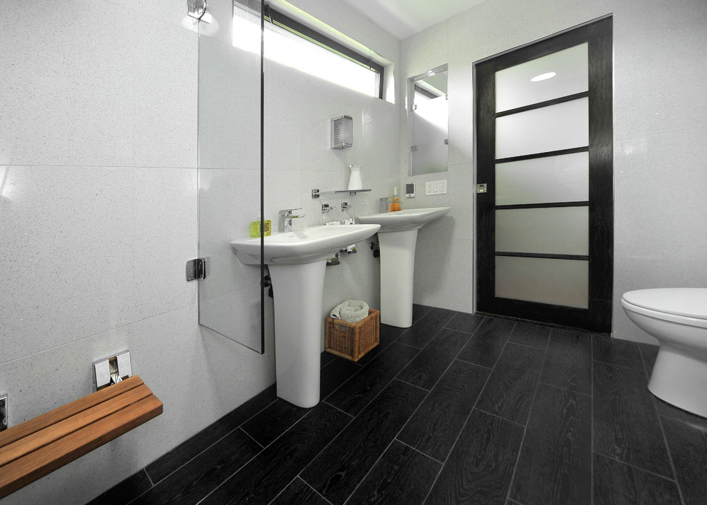 This is an example of a small modern 3/4 bathroom in Los Angeles with a pedestal sink, a curbless shower, a one-piece toilet, white tile, porcelain tile, white walls and porcelain floors.