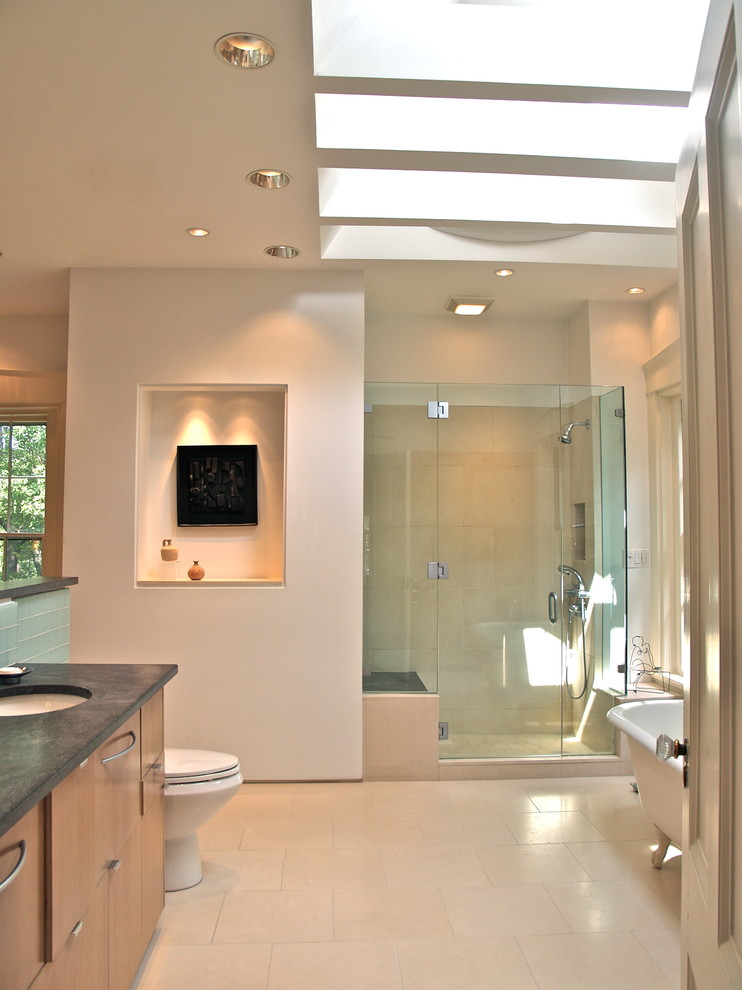 Photo of a large transitional master bathroom in Toronto with an undermount sink, flat-panel cabinets, medium wood cabinets, granite benchtops, a claw-foot tub, a corner shower, a one-piece toilet, blue tile, glass tile, white walls and limestone floors.