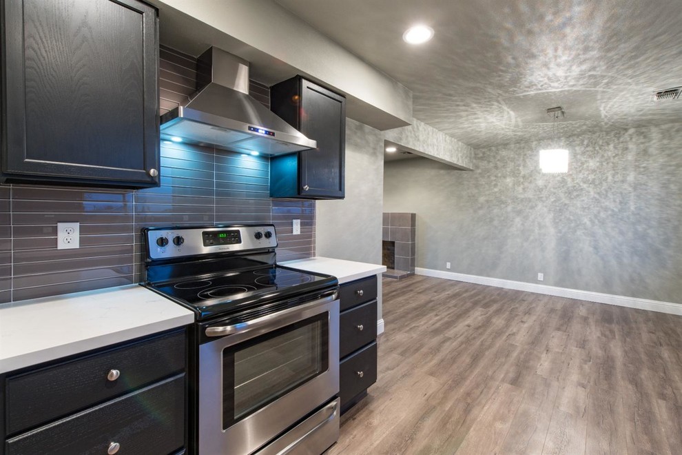 Enclosed kitchen - large transitional galley dark wood floor and brown floor enclosed kitchen idea with an undermount sink, recessed-panel cabinets, black cabinets, quartz countertops, brown backsplash, glass sheet backsplash, stainless steel appliances and no island