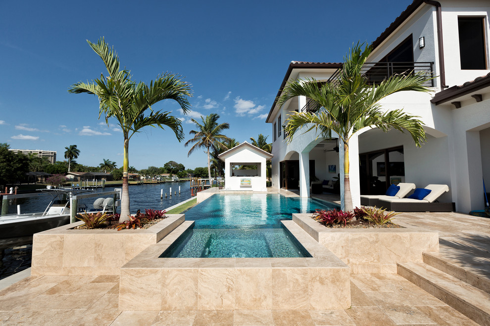 This is an example of a mediterranean infinity pool in Miami with a hot tub and tile.