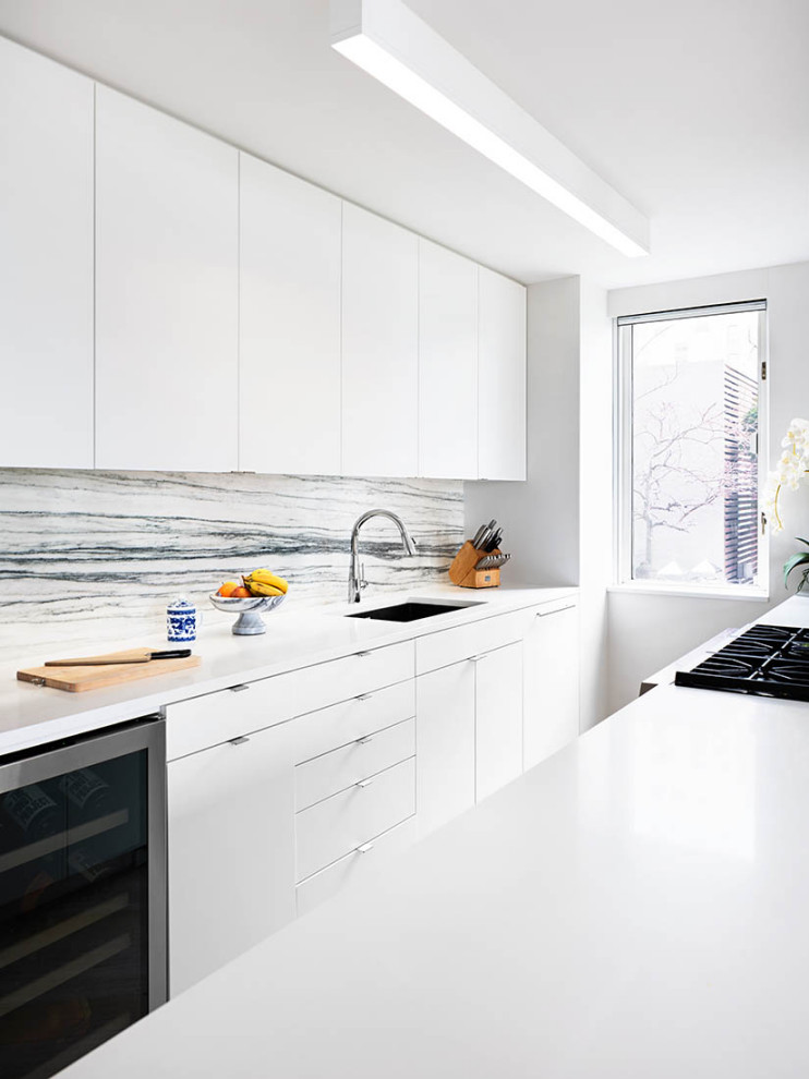 This is an example of a large modern galley eat-in kitchen in New York with an undermount sink, flat-panel cabinets, white cabinets, quartz benchtops, grey splashback, stone slab splashback, panelled appliances, ceramic floors, a peninsula, beige floor and yellow benchtop.
