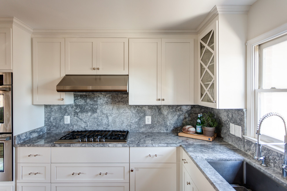 Inspiration for a transitional light wood floor kitchen pantry remodel with a single-bowl sink, shaker cabinets, white cabinets, quartzite countertops, gray backsplash, stone slab backsplash, stainless steel appliances and an island