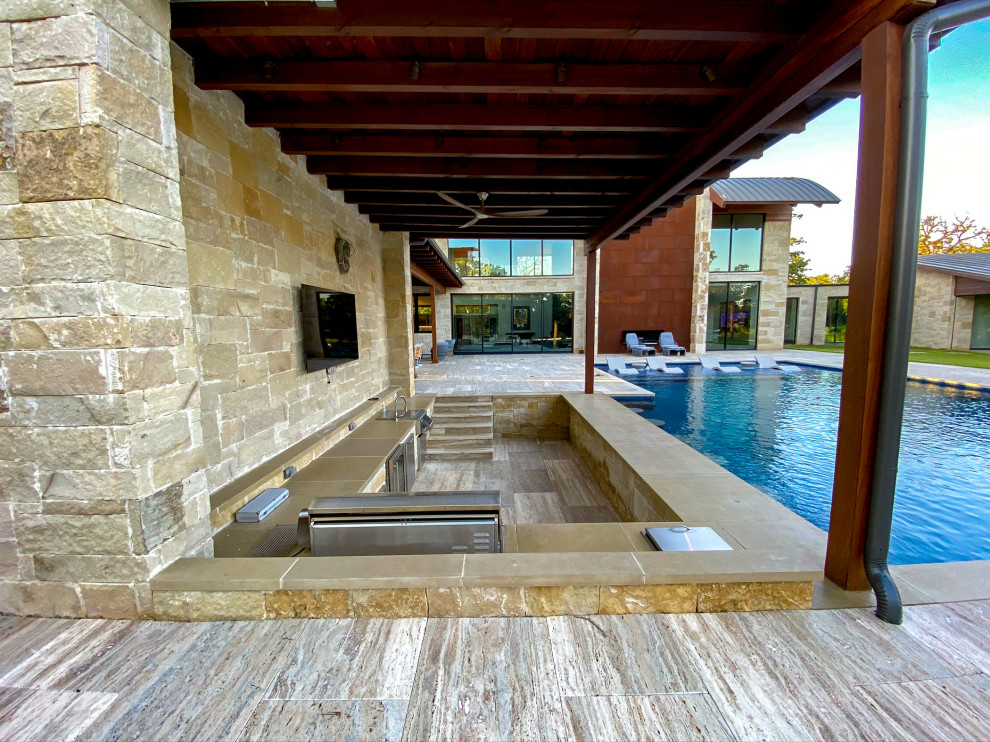 Inspiration for an expansive transitional backyard rectangular infinity pool in Dallas with a water feature and natural stone pavers.