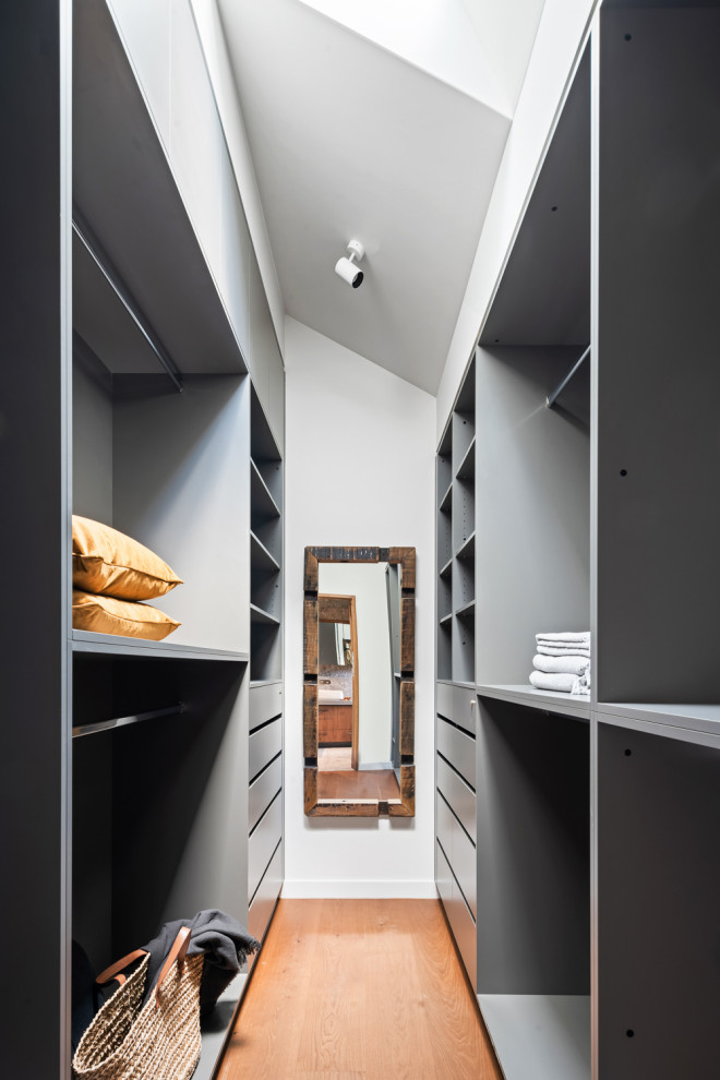 Design ideas for a scandinavian walk-in wardrobe in Melbourne with medium hardwood floors and vaulted.