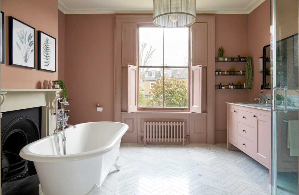 Design ideas for a large transitional master bathroom in London with pink walls, marble benchtops, a double vanity, recessed-panel cabinets, a freestanding tub, an open shower, a two-piece toilet, porcelain floors, an undermount sink, grey floor, a hinged shower door, grey benchtops and a freestanding vanity.
