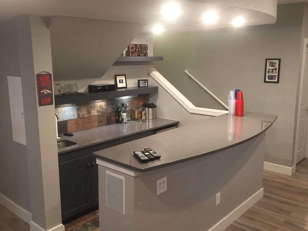 Design ideas for a mid-sized transitional single-wall seated home bar in Denver with an undermount sink, grey cabinets, shaker cabinets, quartz benchtops, brown splashback, metal splashback, medium hardwood floors and brown floor.
