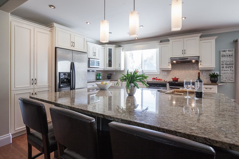 Mid-sized transitional l-shaped medium tone wood floor and brown floor eat-in kitchen photo with an undermount sink, granite countertops, beige backsplash, stone tile backsplash, stainless steel appliances, an island, recessed-panel cabinets and white cabinets