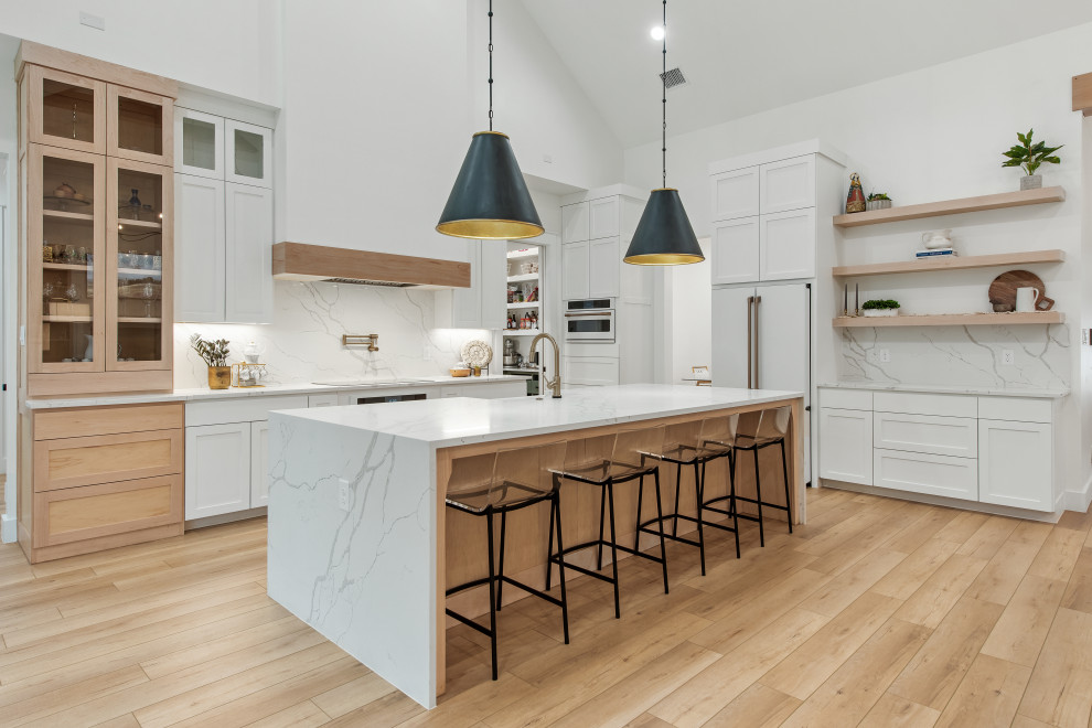 Design ideas for a mid-sized scandinavian l-shaped open plan kitchen in Dallas with a farmhouse sink, shaker cabinets, white cabinets, quartz benchtops, white splashback, engineered quartz splashback, white appliances, vinyl floors, with island, white benchtop and exposed beam.