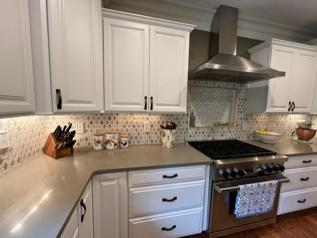 Example of a large transitional u-shaped medium tone wood floor and brown floor eat-in kitchen design with raised-panel cabinets, yellow cabinets, quartz countertops, green backsplash, mosaic tile backsplash, stainless steel appliances, an island and green countertops