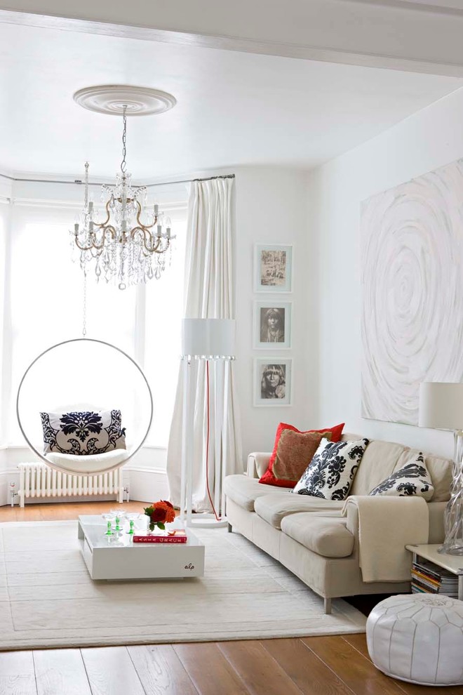 This is an example of a transitional open concept living room in London with white walls and medium hardwood floors.