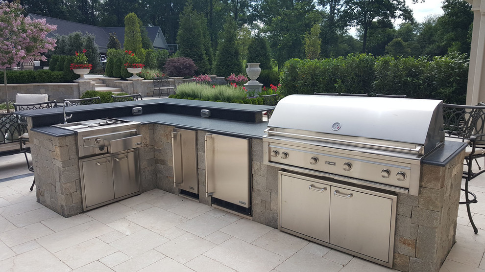 This is an example of a large traditional backyard patio in DC Metro with an outdoor kitchen, natural stone pavers and no cover.