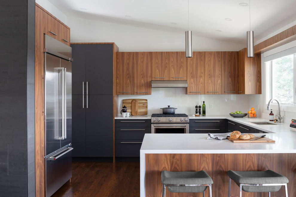 Photo of a large contemporary u-shaped eat-in kitchen in Calgary with an undermount sink, flat-panel cabinets, medium wood cabinets, quartz benchtops, white splashback, stone slab splashback, stainless steel appliances, dark hardwood floors, a peninsula, brown floor and white benchtop.