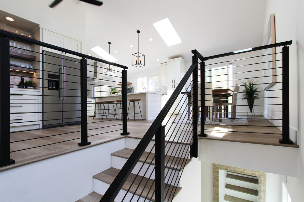 Example of a mid-sized transitional l-shaped vinyl floor, brown floor and vaulted ceiling eat-in kitchen design with an undermount sink, shaker cabinets, white cabinets, quartz countertops, multicolored backsplash, mosaic tile backsplash, stainless steel appliances, an island and white countertops