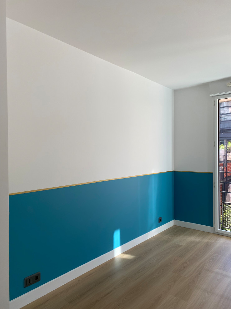 Immagine di una cameretta per bambini da 4 a 10 anni moderna di medie dimensioni con pareti blu, pavimento in laminato e pavimento beige