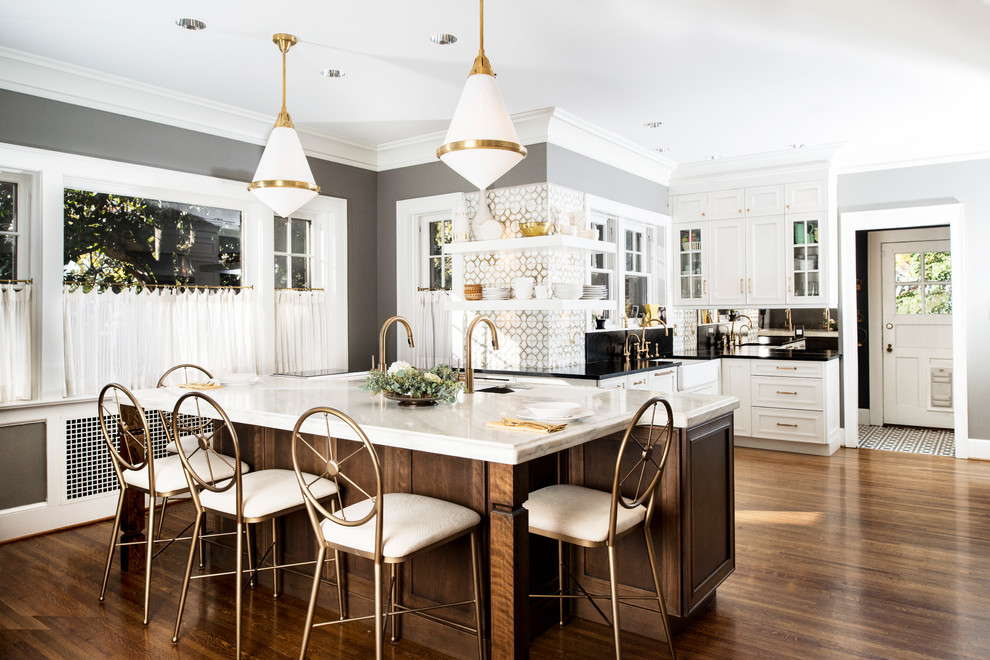 Eat-in kitchen - large transitional u-shaped medium tone wood floor and brown floor eat-in kitchen idea with marble countertops, white backsplash, glass tile backsplash, stainless steel appliances, an island, a farmhouse sink, recessed-panel cabinets and white cabinets