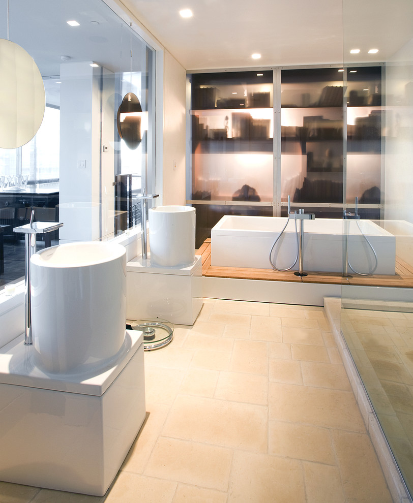 Contemporary bathroom in Seattle with a pedestal sink, white cabinets, beige tile, stone tile and a freestanding tub.