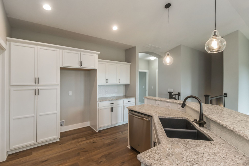 Kitchen - large transitional u-shaped brown floor and light wood floor kitchen idea with an undermount sink, shaker cabinets, white cabinets, quartz countertops, white backsplash, glass tile backsplash, stainless steel appliances, an island and multicolored countertops