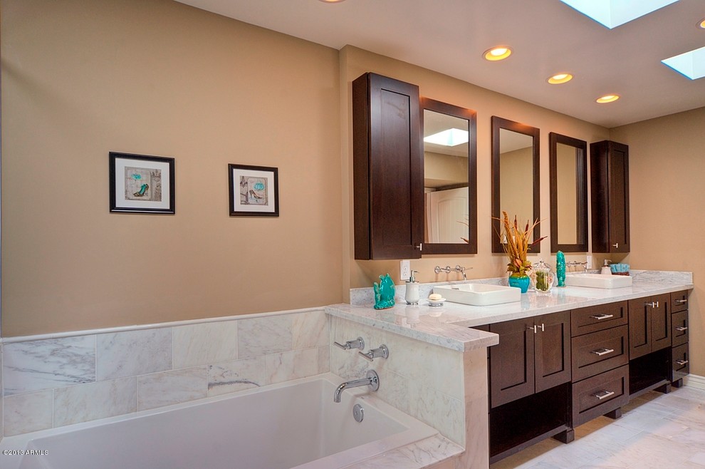 This is an example of a mid-sized transitional bathroom in Phoenix with a vessel sink, shaker cabinets, dark wood cabinets, marble benchtops, an alcove tub, a corner shower, white tile, stone tile, beige walls and marble floors.