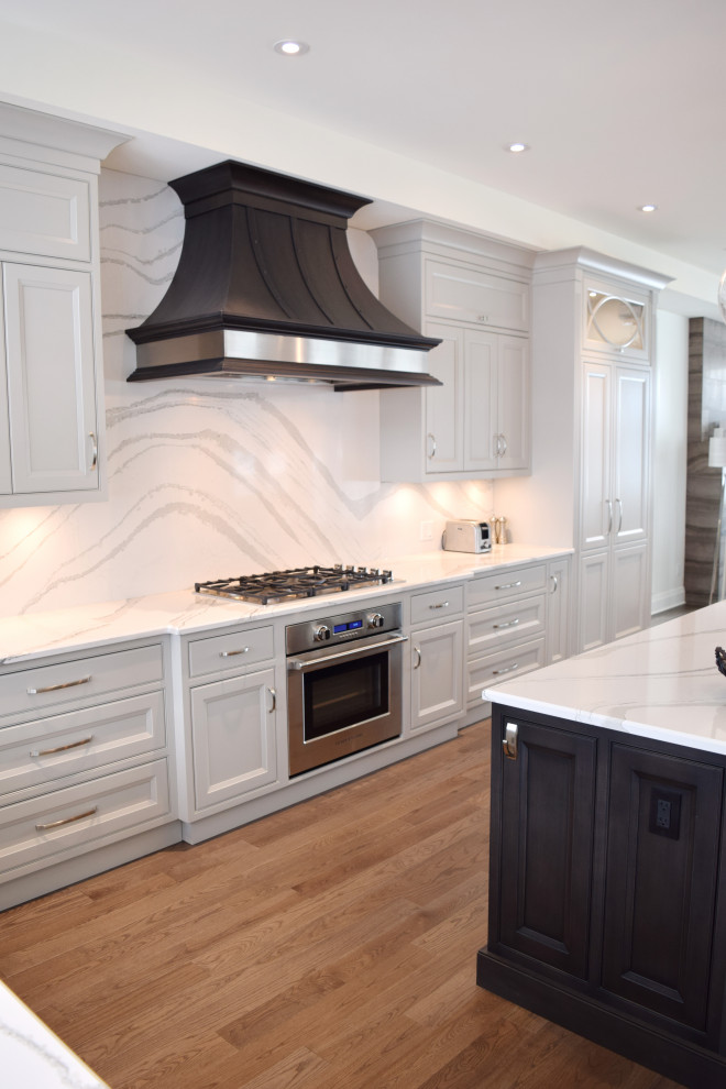 Example of a large l-shaped medium tone wood floor and brown floor open concept kitchen design in Ottawa with an undermount sink, recessed-panel cabinets, white cabinets, quartz countertops, white backsplash, quartz backsplash, paneled appliances, an island and white countertops