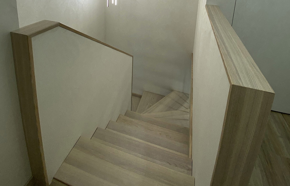 Пример оригинального дизайна: изогнутая деревянная лестница среднего размера в современном стиле с крашенными деревянными ступенями, деревянными перилами и обоями на стенах