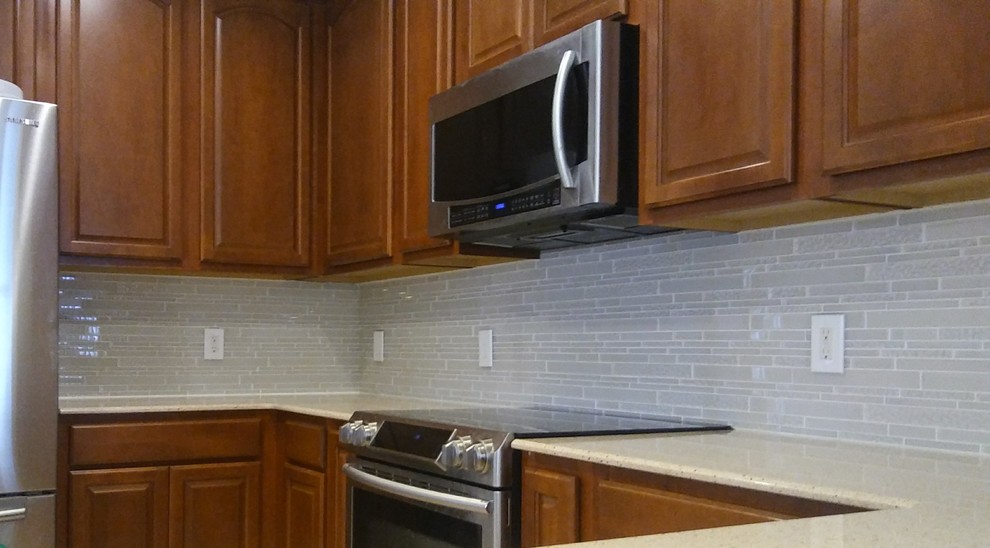 Inspiration for a mid-sized transitional l-shaped eat-in kitchen remodel with quartz countertops, white backsplash, glass tile backsplash and a peninsula