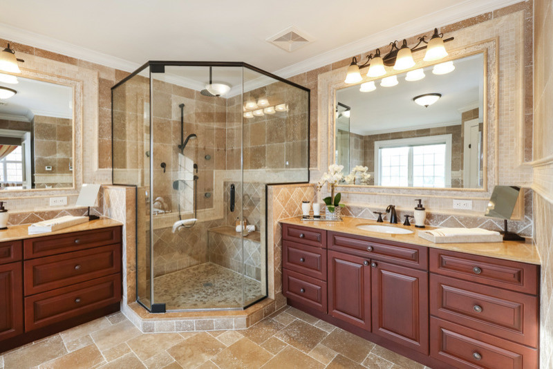 Large traditional master bathroom in New York with raised-panel cabinets, brown cabinets, a drop-in tub, a corner shower, a one-piece toilet, beige tile, ceramic tile, beige walls, ceramic floors, a drop-in sink, granite benchtops, beige floor and a hinged shower door.