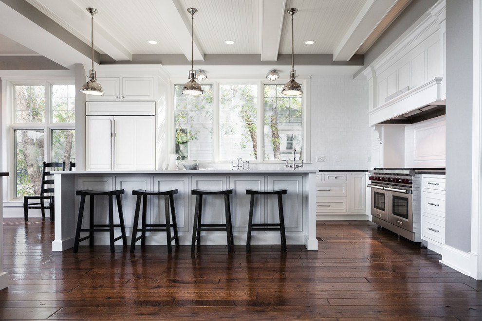 Inspiration for a large beach style l-shaped open plan kitchen in Milwaukee with beaded inset cabinets, white cabinets, quartz benchtops, white splashback, panelled appliances, dark hardwood floors, with island and brown floor.