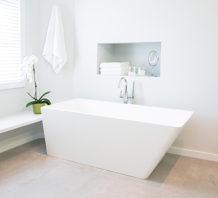 Large scandinavian master bathroom in Toronto with flat-panel cabinets, light wood cabinets, a freestanding tub, a corner shower, a two-piece toilet, gray tile, white tile, glass tile, white walls, cement tiles, an undermount sink and solid surface benchtops.