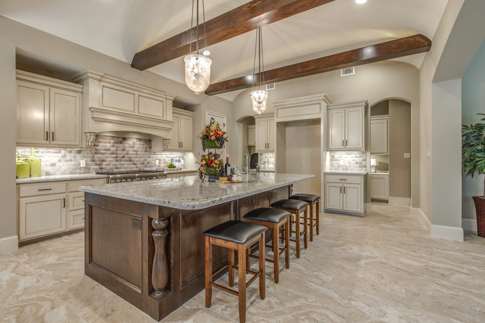 Design ideas for a large mediterranean l-shaped eat-in kitchen in Houston with an undermount sink, recessed-panel cabinets, white cabinets, granite benchtops, beige splashback, ceramic splashback, stainless steel appliances, ceramic floors, with island and beige floor.
