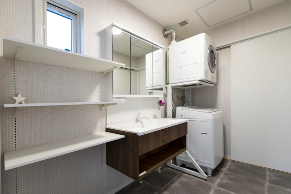 Photo of a modern dedicated laundry room in Other with dark wood cabinets, white walls, a stacked washer and dryer, multi-coloured floor, wallpaper and wallpaper.