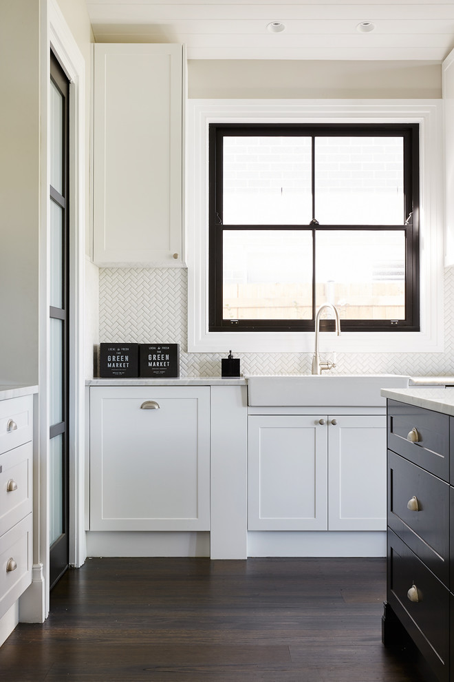 This is an example of a mid-sized traditional l-shaped eat-in kitchen in Sydney with a farmhouse sink, shaker cabinets, black cabinets, marble benchtops, white splashback, ceramic splashback, stainless steel appliances, dark hardwood floors, with island and black floor.