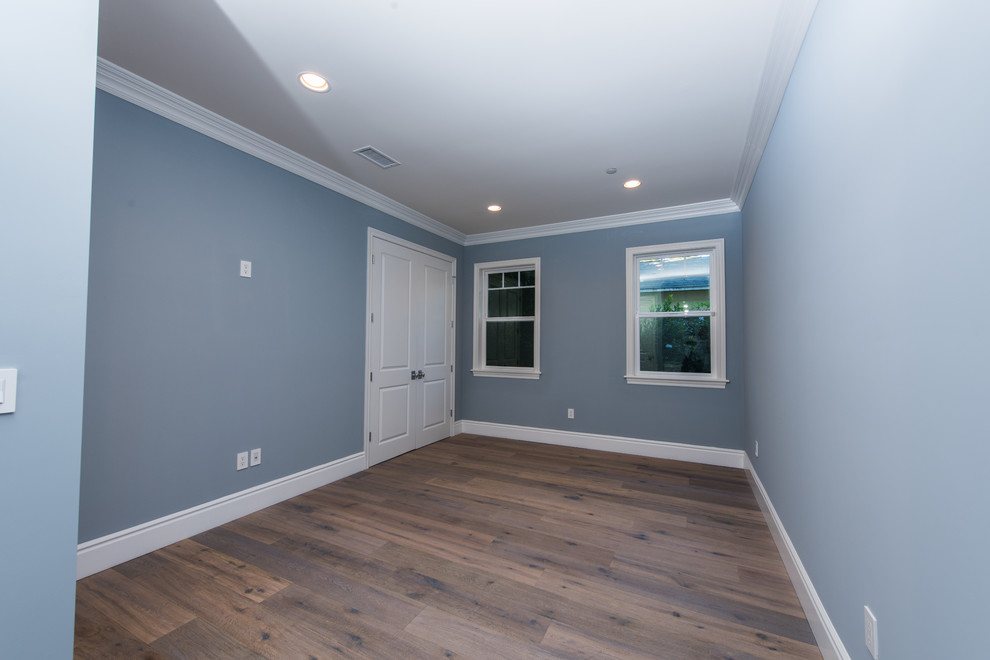 Modelo de habitación de invitados actual de tamaño medio con paredes azules y suelo de madera oscura