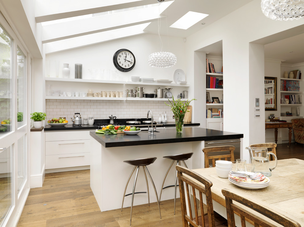 Photo of a large contemporary kitchen in London with flat-panel cabinets, white cabinets, solid surface benchtops and an undermount sink.