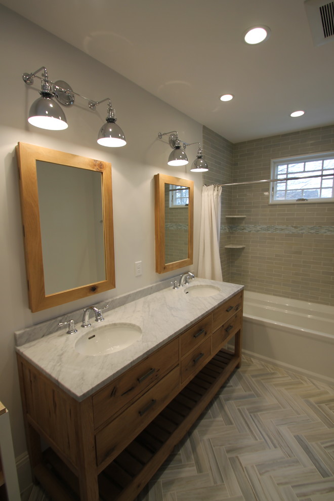 Inspiration for a mid-sized transitional bathroom in Boston with furniture-like cabinets, light wood cabinets, an alcove tub, a shower/bathtub combo, beige tile, ceramic tile, white walls, an undermount sink and marble benchtops.