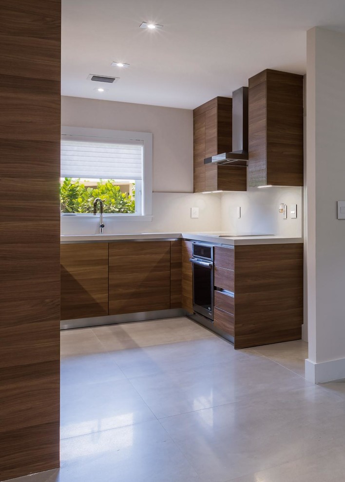 Photo of a mid-sized contemporary l-shaped separate kitchen in Miami with an integrated sink, flat-panel cabinets, dark wood cabinets, soapstone benchtops, white splashback, stone slab splashback, stainless steel appliances, marble floors, no island and beige floor.