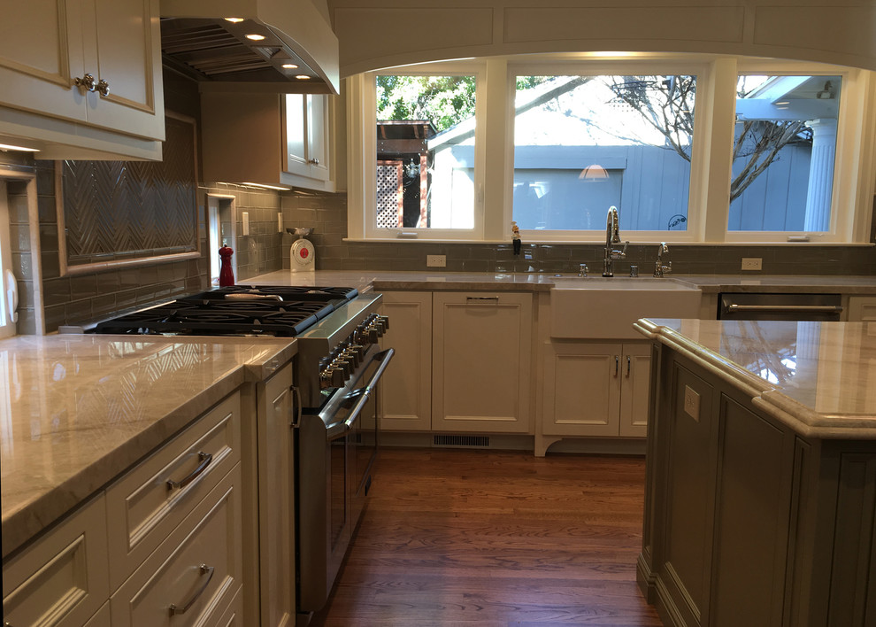 Mid-sized transitional u-shaped medium tone wood floor and brown floor eat-in kitchen photo in San Francisco with a farmhouse sink, shaker cabinets, white cabinets, marble countertops, gray backsplash, subway tile backsplash, stainless steel appliances, an island and gray countertops