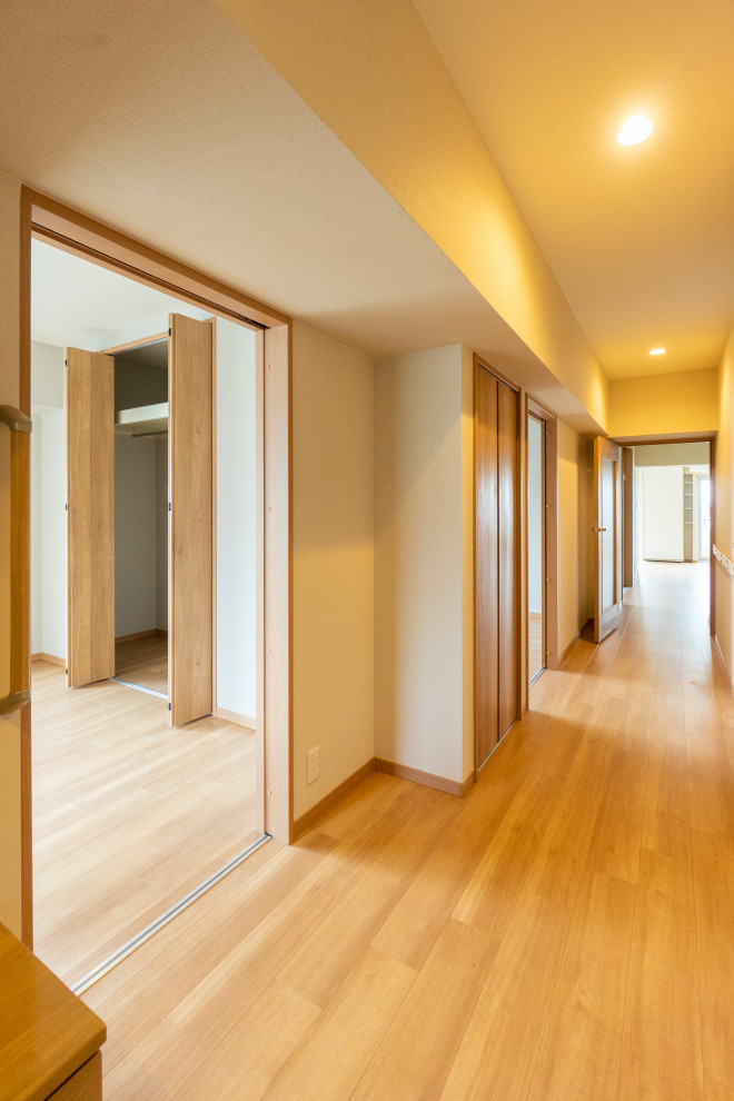 This is an example of a hallway in Kobe with white walls, plywood floors, brown floor, wallpaper and wallpaper.