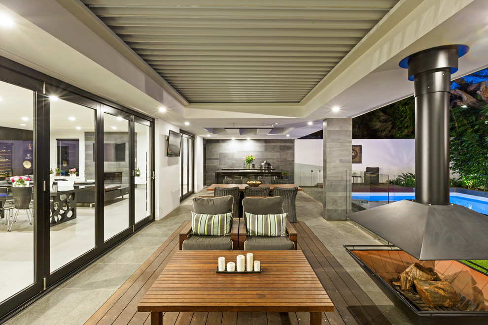 Contemporary patio in Melbourne with a roof extension and with fireplace.