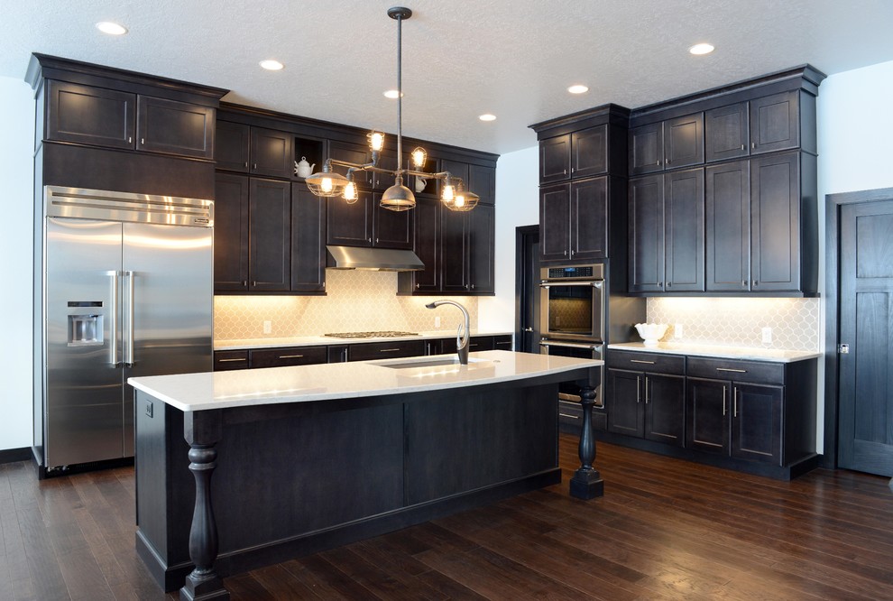Inspiration for a large transitional l-shaped medium tone wood floor open concept kitchen remodel with an undermount sink, shaker cabinets, dark wood cabinets, quartz countertops, gray backsplash, porcelain backsplash, stainless steel appliances and an island