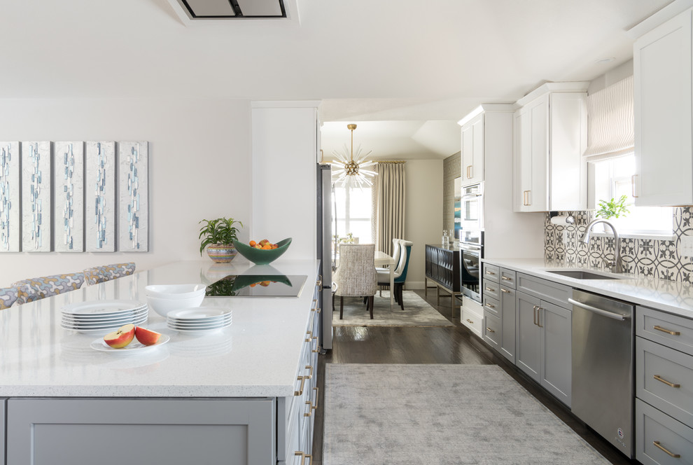 This is an example of a mid-sized traditional galley eat-in kitchen in Dallas with an undermount sink, shaker cabinets, grey cabinets, quartz benchtops, grey splashback, cement tile splashback, stainless steel appliances, medium hardwood floors, a peninsula and brown floor.