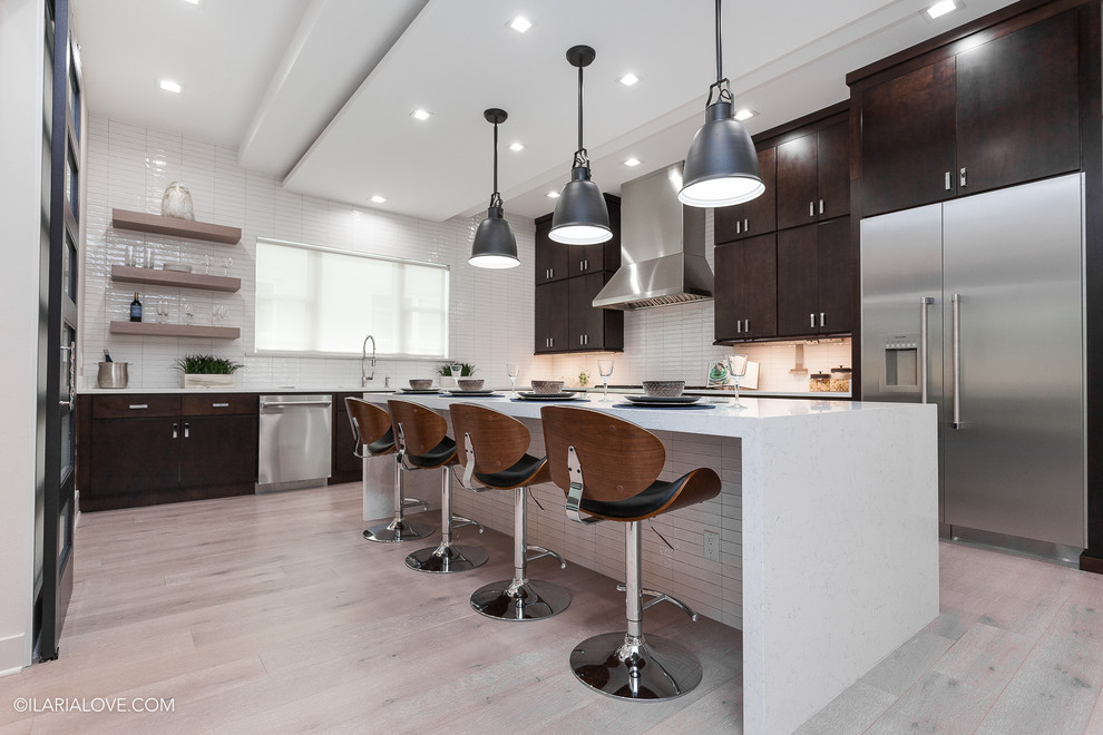 This is an example of a mid-sized contemporary l-shaped separate kitchen in Orlando with flat-panel cabinets, dark wood cabinets, quartz benchtops, white splashback, stainless steel appliances, with island, matchstick tile splashback, vinyl floors, an undermount sink and grey floor.