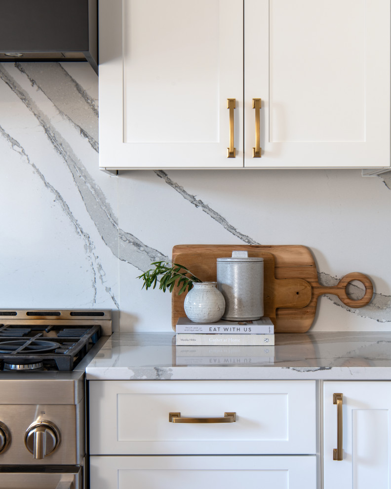Example of a mid-sized transitional u-shaped light wood floor and brown floor eat-in kitchen design in Ottawa with an undermount sink, shaker cabinets, white cabinets, quartz countertops, white backsplash, quartz backsplash, stainless steel appliances, a peninsula and white countertops
