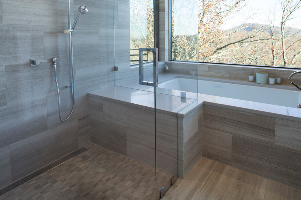 Photo of a large contemporary master bathroom in Other with flat-panel cabinets, dark wood cabinets, an undermount tub, a shower/bathtub combo, a one-piece toilet, gray tile, stone tile, grey walls, limestone floors, a vessel sink and engineered quartz benchtops.