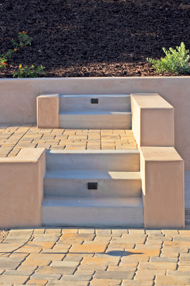 Example of a tuscan backyard concrete paver patio design in San Luis Obispo with a pergola