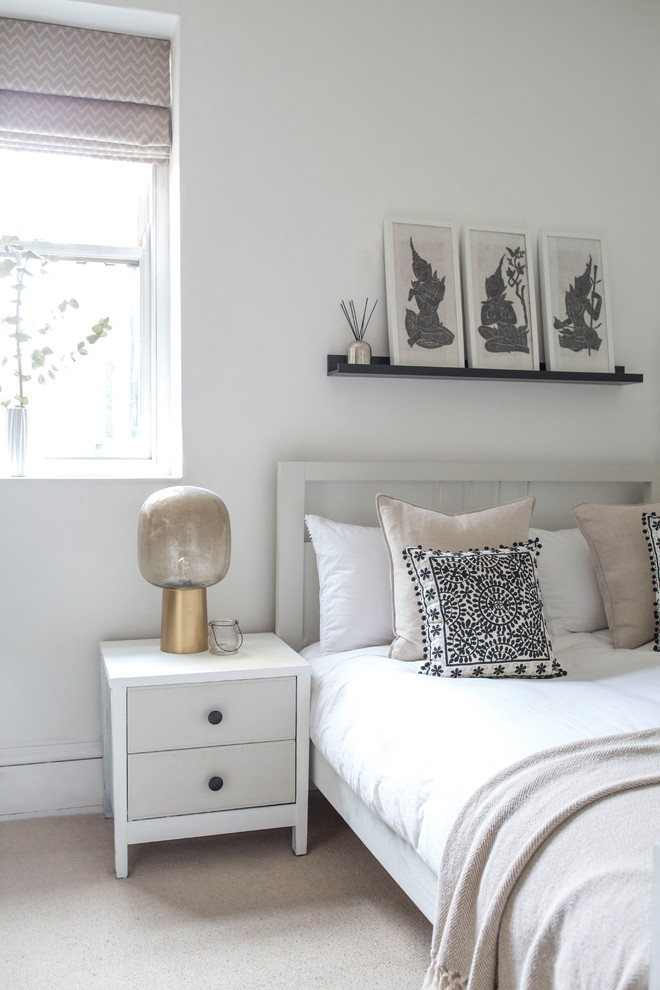 This is an example of a mid-sized scandinavian bedroom in London with white walls, carpet, no fireplace and beige floor.