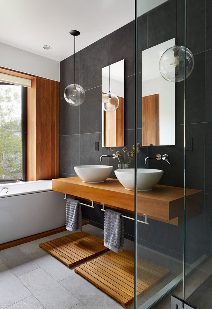 Inspiration for a contemporary master bathroom in New York with a drop-in tub, a corner shower, black tile, black walls, a vessel sink, wood benchtops and grey floor.