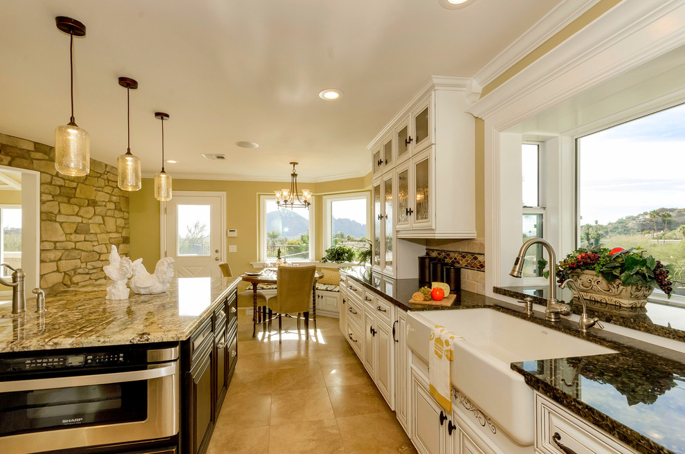 Inspiration for a large transitional u-shaped eat-in kitchen in Phoenix with a farmhouse sink, white cabinets, granite benchtops, stainless steel appliances, ceramic floors, with island, glass-front cabinets, beige splashback and cement tile splashback.