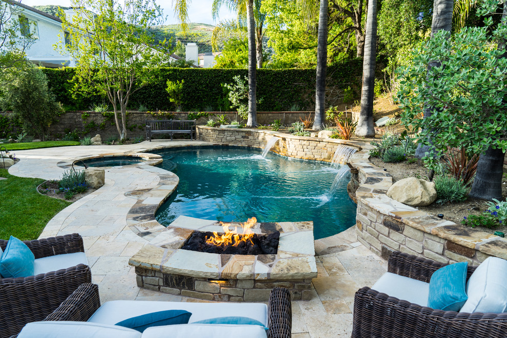 Inspiration for a country backyard custom-shaped pool in Los Angeles with natural stone pavers.