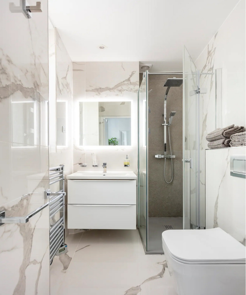 На фото: маленькая ванная комната в стиле модернизм с плоскими фасадами, белыми фасадами, душем без бортиков, унитазом-моноблоком, белой плиткой, мраморной плиткой, белыми стенами, мраморным полом, душевой кабиной, настольной раковиной, белым полом, душем с распашными дверями, белой столешницей, тумбой под одну раковину, подвесной тумбой и многоуровневым потолком для на участке и в саду с