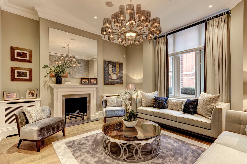 This is an example of a large transitional formal enclosed living room in London with beige walls, medium hardwood floors, a standard fireplace and a metal fireplace surround.
